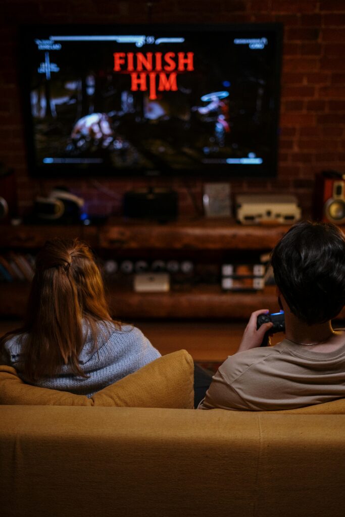 A couple sitting on a couch playing video games in a cozy living room during the evening.