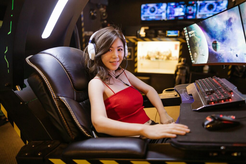 A woman seated at an advanced gaming setup featuring a scorpion gaming chair, multiple monitors, and gaming peripherals. content