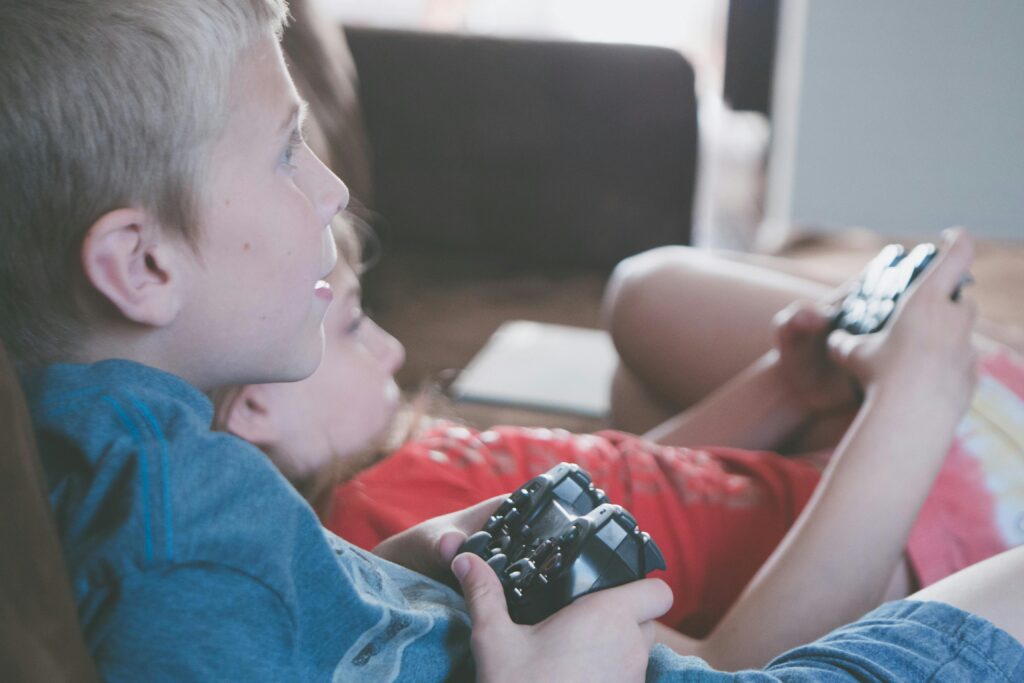 Two children playing video games together with controllers indoors.