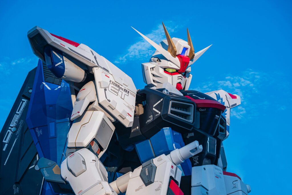 Close-up of a giant Gundam robot statue set against a clear blue sky.